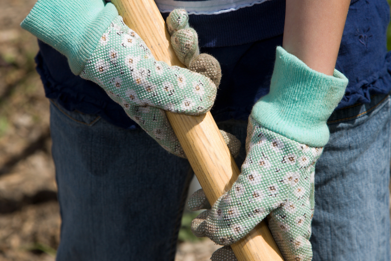 hands with gardening gloves holding rake