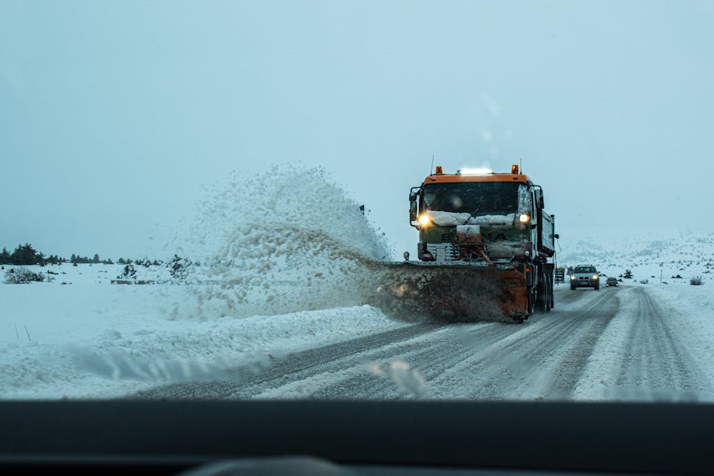 A snow plow clears a snow-covered road during winter, ensuring safe transportation for vehicles.