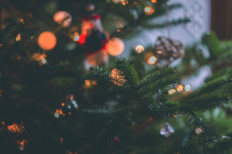 Close-up of a beautifully decorated Christmas tree with glowing bokeh lights, capturing festive warmth.