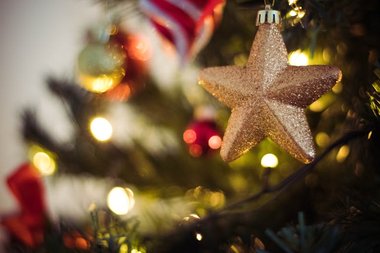 Close-up of a sparkling golden star ornament hanging on a decorated Christmas tree.