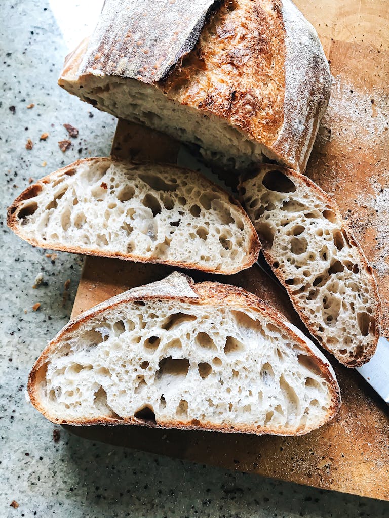 Freshly baked sourdough bread with airy crumb, sliced on a cutting board. Perfect for breakfast or snack.