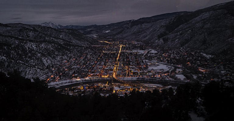 Captivating aerial night view of Glenwood Springs, CO in winter, highlighting urban lights.