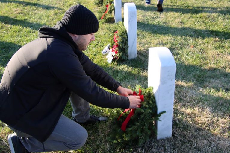 man laying wreath in cemetary