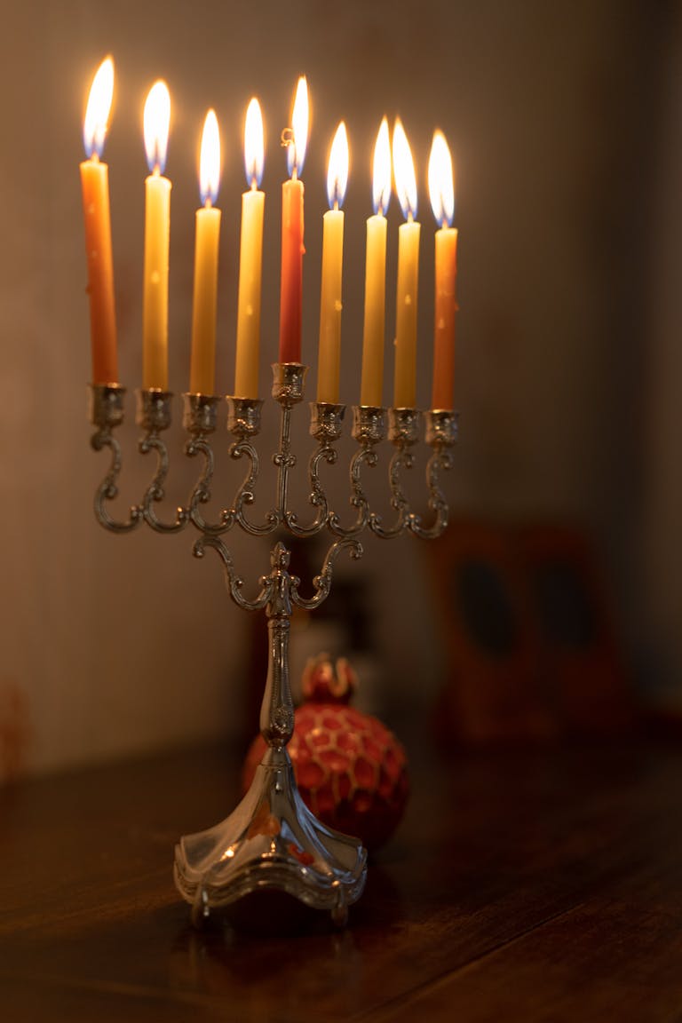 A silver menorah with candles lit for Hanukkah, symbolizing Jewish tradition and celebration.
