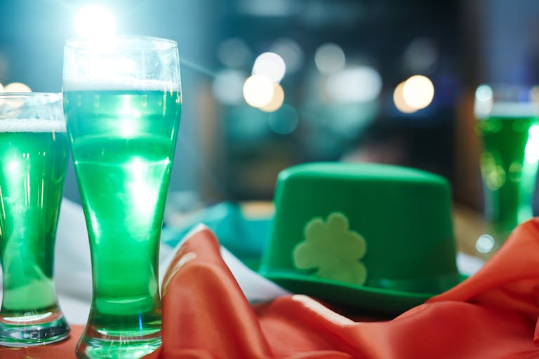 Close-up of green beer and a green hat with a shamrock symbol, perfect for Saint Patrick's Day celebrations.