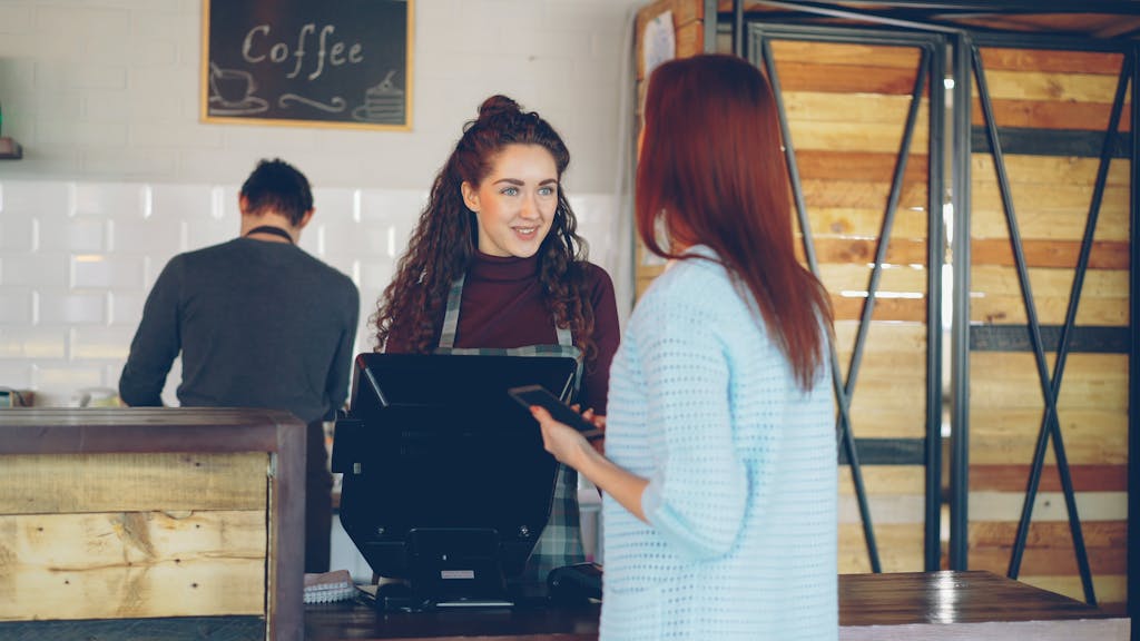 Barista engaging with customer at a cozy café for coffee service.
