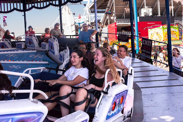 Group of friends enjoying a thrilling ride at an amusement park during the day.
