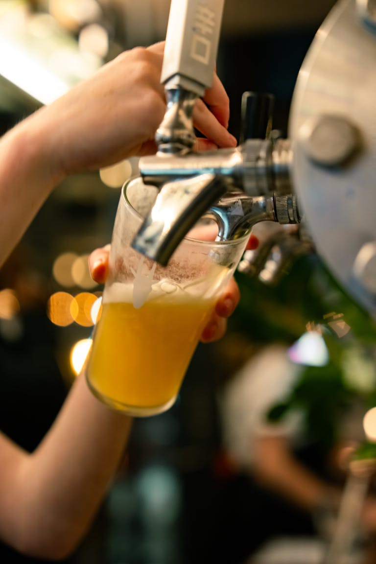 Hand pouring fresh draft beer into a pint glass at a bar. Perfect for beverage and lifestyle themes.